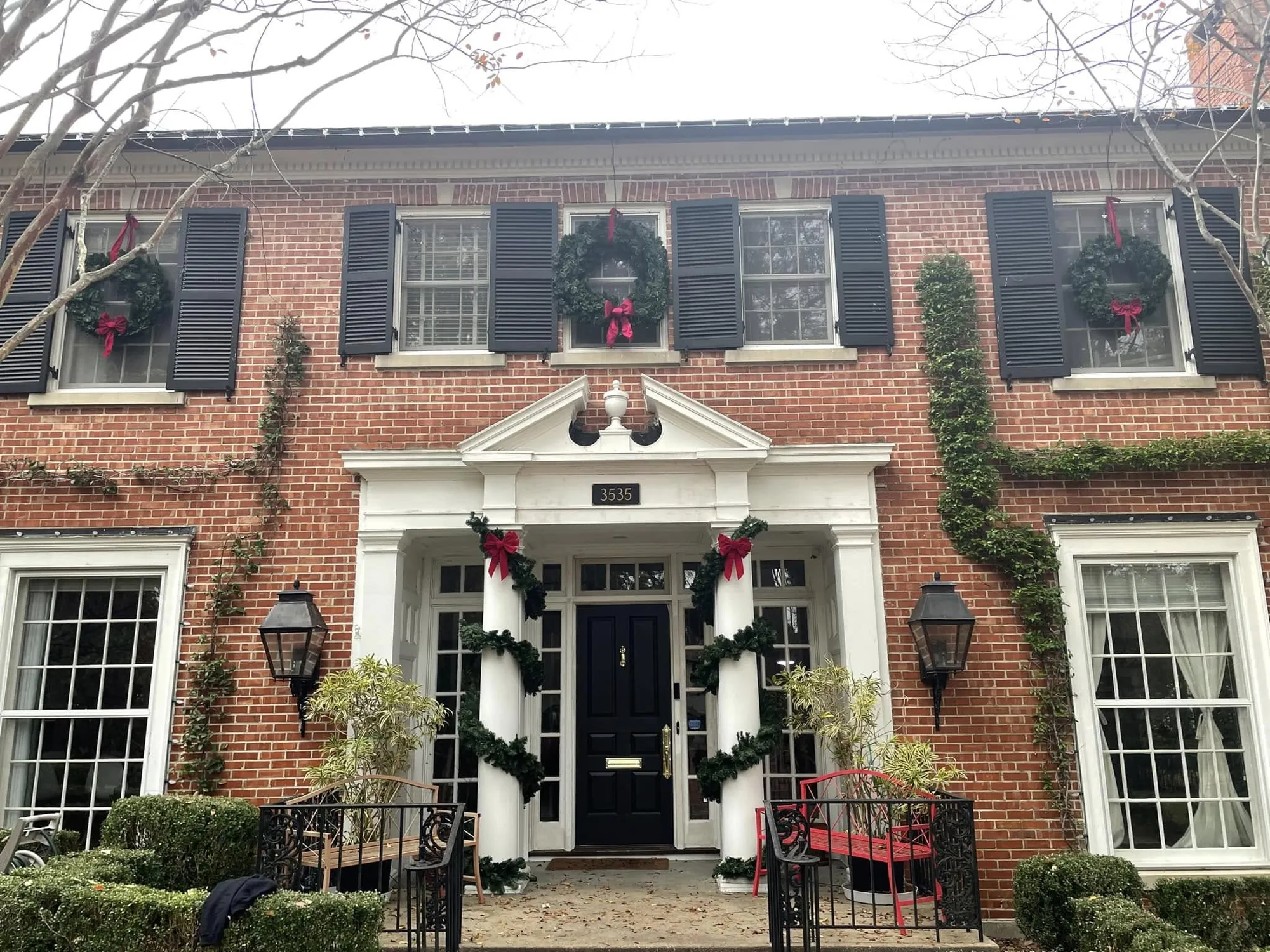 Brick colonial home dressed with wreaths and garland around the front door
