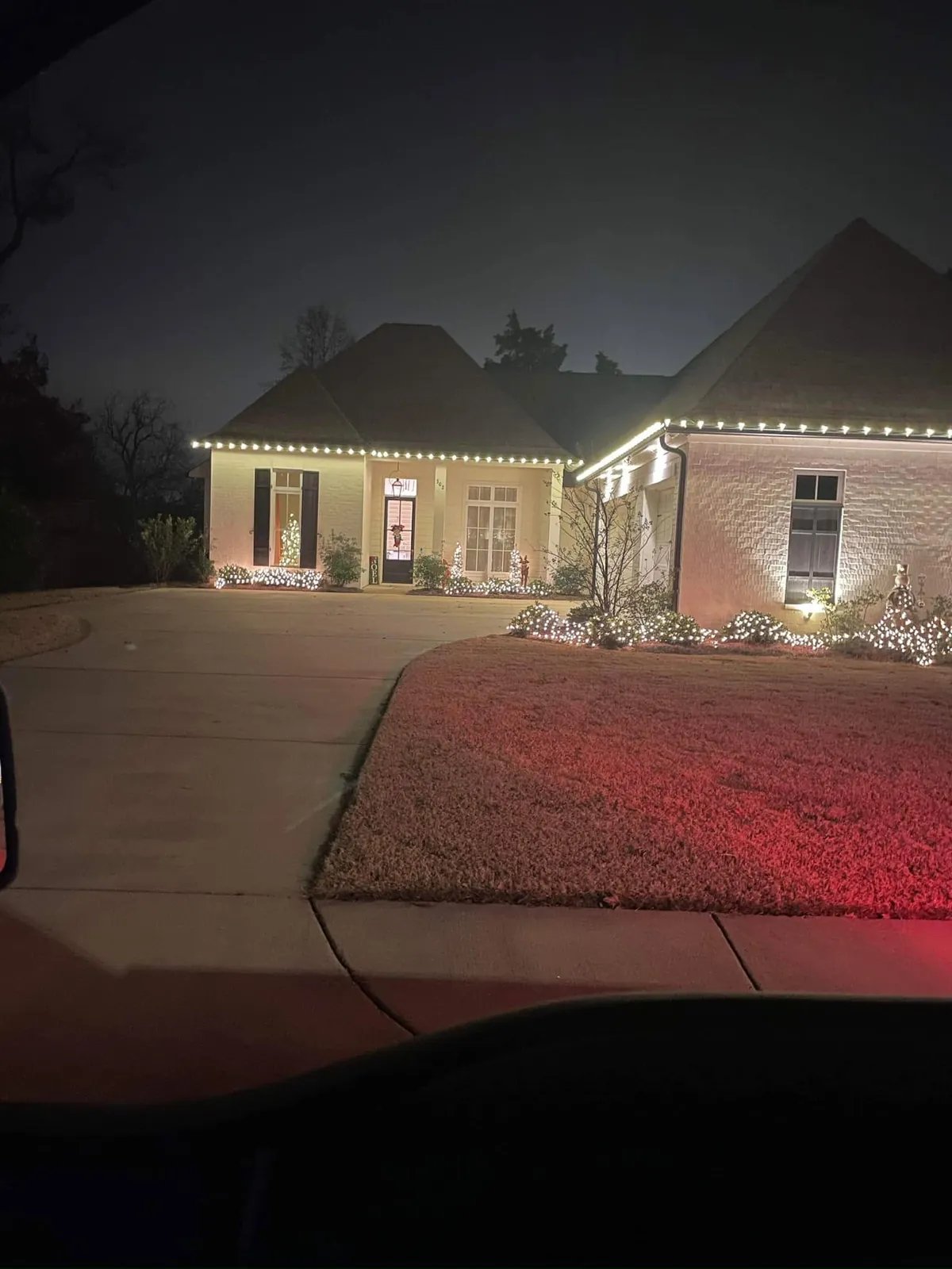 Home glowing at night with red lights washing the driveway